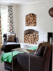 a white brick wall with a non-working fireplace and a couple of matching niches that hold firewood matches the interior and makes it more rustic and cozier