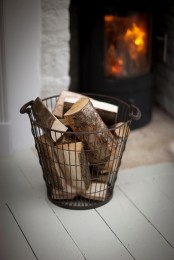 a wire basket with firewood is a cool idea to store it adding coziness and a vintage feel to the space