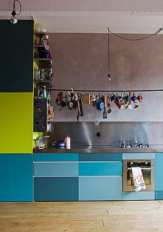 a creatively bright kitchen with bright and metallic blue cabinets and neon green parts, with a stainless steel backsplash and countertops is bold and cool