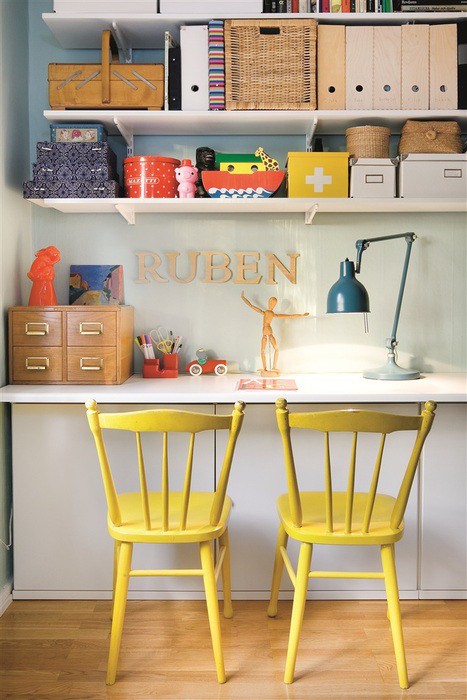 A neutral home office with open shelves, a wall mounted desk, with bright yellow chairs and some colorful boxes for a bolder look