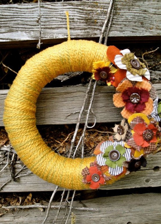 a colorful yarn fall wreath with yellow yarn, fabric blooms and vintage buttons is a cool vintage decoration
