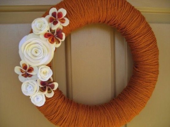 a bright fall wreath covered with rust yarn, with white and rust fabric flowers and beads is a truly fall-colored idea