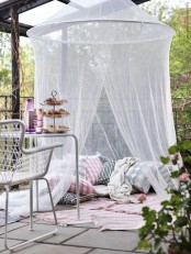 a terrace with a pillow space with rugs and a mosquito net over – invite your kids to spend time there without any bugs