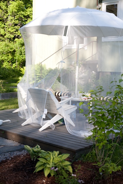 a comfortable sitting zone with chairs, a coffee table, an umbrella and a mosquito net over them all