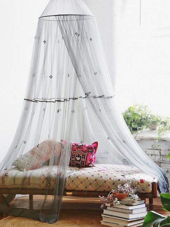 a boho daybed with an embroidered grey mosquito net that adds chic and decor value to the space