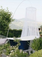 an outdoor navy bathtub with a mosquito net over it to highlight the tub and give it some privacy at the same time