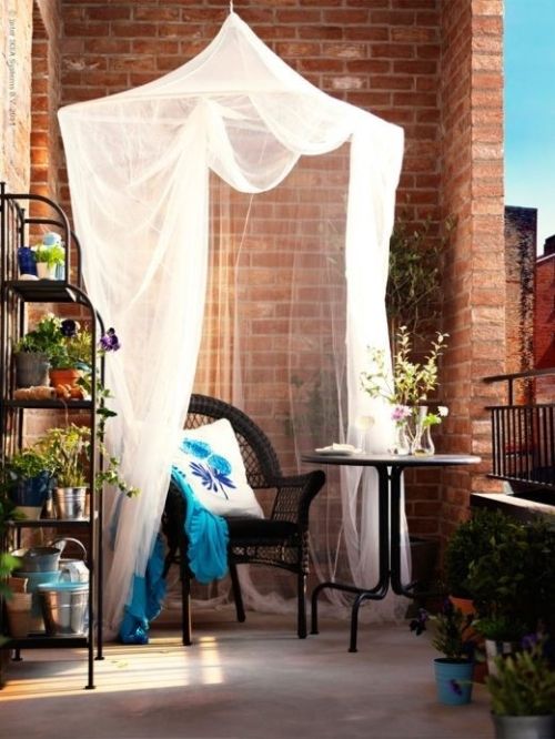 a mosquito net used for decor in a small balcony, it gives a relaxed feel to the red brick space