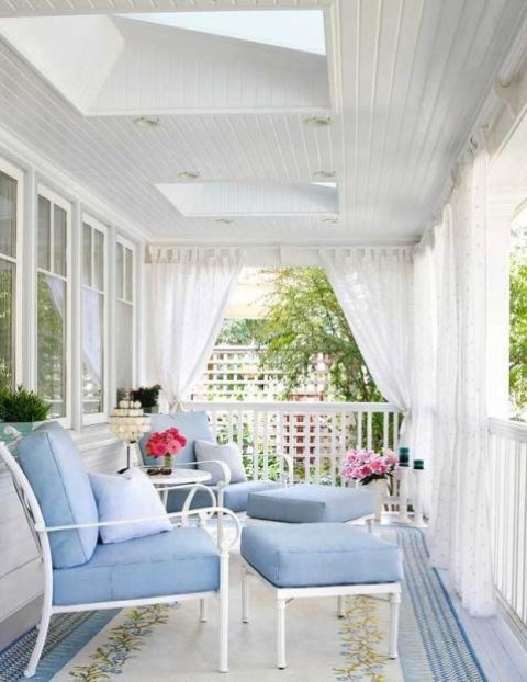 a beautiful porch done with light blue furniture and mosquito net curtains that can give privacy and save from bugs