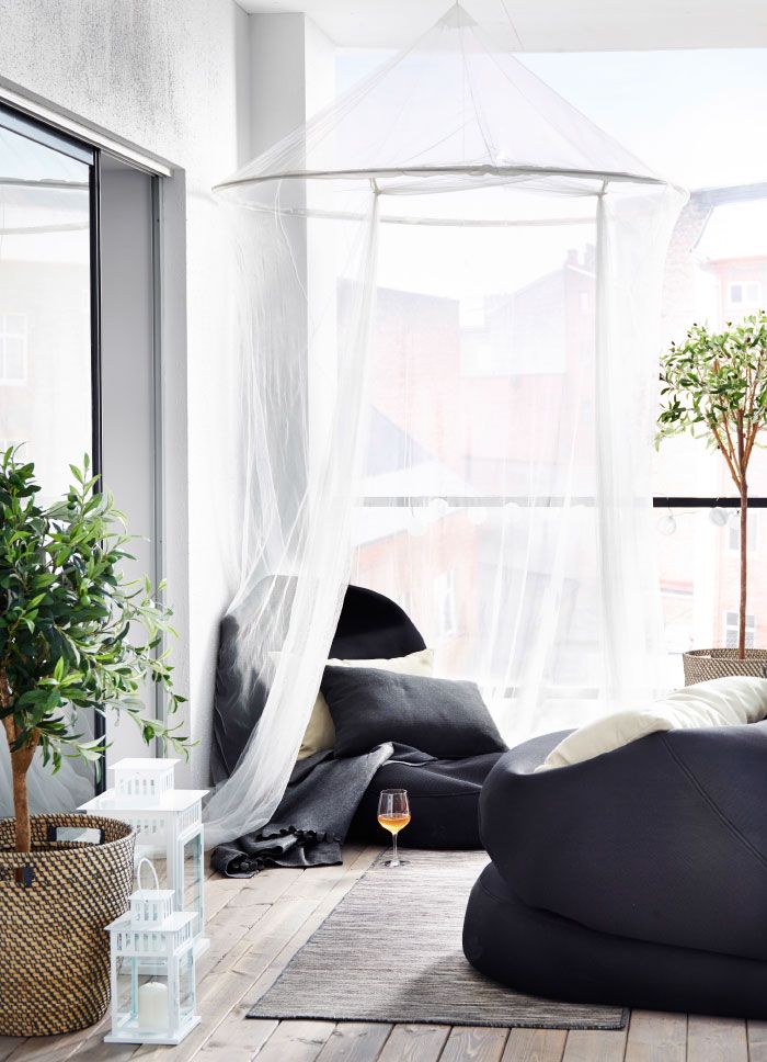 A contemporary balcony with black bean bag chairs and mosquito nets over them   both for decor and to avoid bugs