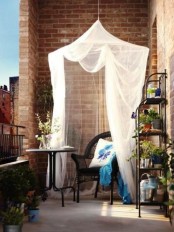 a small stting space on a balcony – a coffee table and a wicker chair covered with a mosquito net for more comfort
