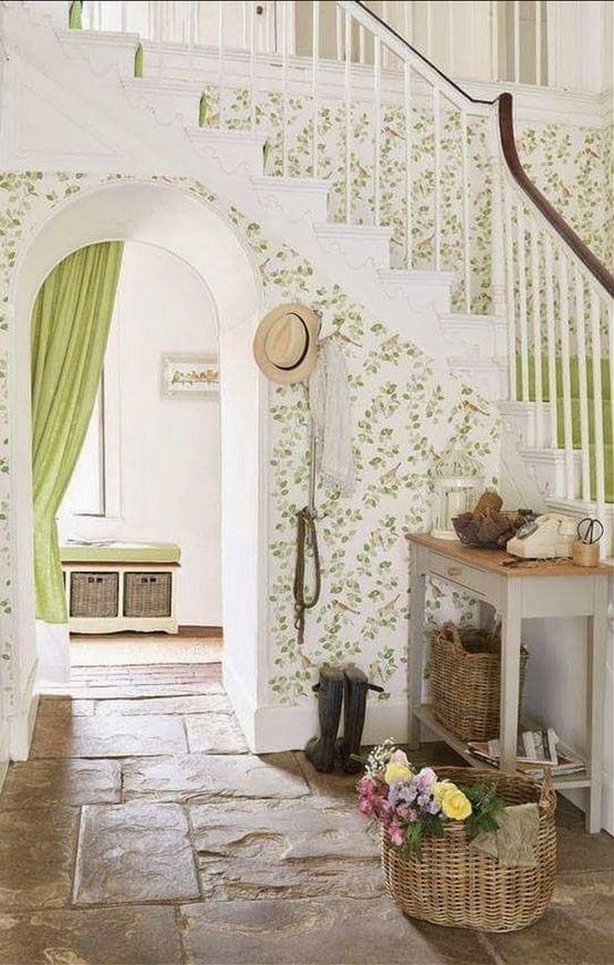 A cute neutral and green entryway with printed wallpaper, a console table, baskets and a storage bench with baskets