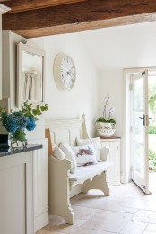 a neutral shabby chic entryway with a carved wooden bench, a vintage clock and a framed mirror