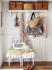 a shabby chic entryway with a shelf with baskets, chairs, woven bags anf cute clothes