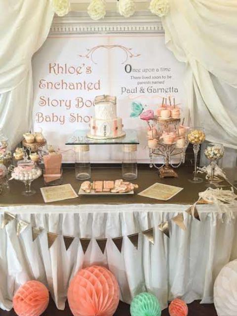 a gender neutral dessert table done in mint and coral, with a framed sign showing a story book and curtains