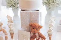 a neutral dessert table with baby’s breath, a teddy bear, a teddy bear cake looks totally gender neutral