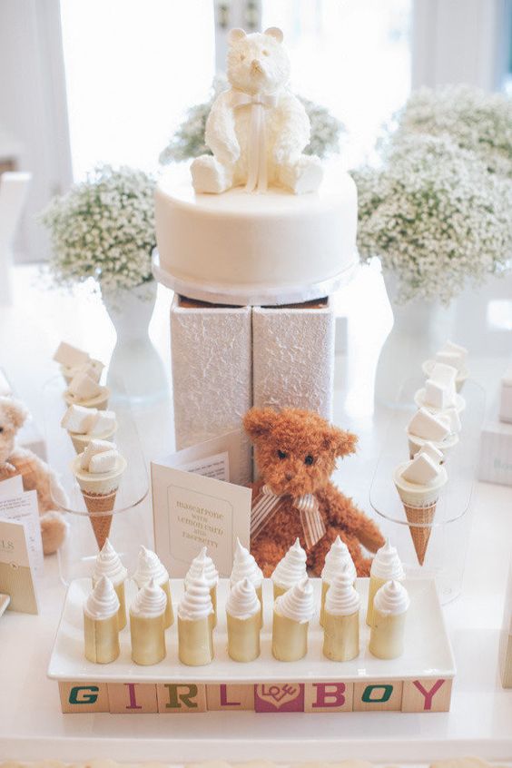 a neutral dessert table with baby's breath, a teddy bear, a teddy bear cake looks totally gender neutral