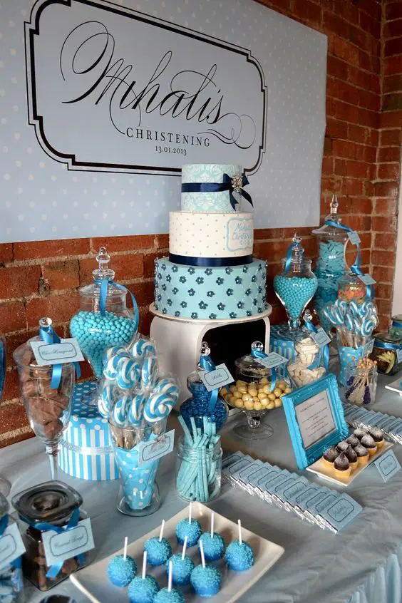 a turquoise and blue dessert table with lots of sweets displayed in jars, on plates, glasses and a large wedding cake on a stand