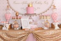 a bright pink and gold dessert table with a letter backdrop, a gold sequin tablecloth, refined stands and bowls