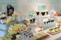 a gender neutral baby shower dessert table done in blue and green, with lots of Mickey Mouse desserts and decorations