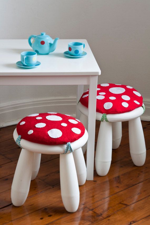 A white table and white IKEA Mammut stools spruced up with bright mushroom inspired pillows to look whimsy