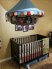 a cheerful circus-themed yellow and blue nursery with a dark IKEA Sundvik crib and dark frames for the pics