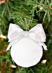 a snowball with a silver bow is a cool and cute Christmas ornament to rock