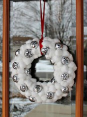 a snowball and bell Christmas wreath on a red ribbon is a lovely outdoor Christmas decoration