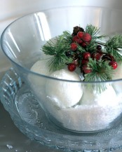a clear bowl with snow, snowballs, fir twigs, berries on top is a lovely and chic Christmas centerpiece