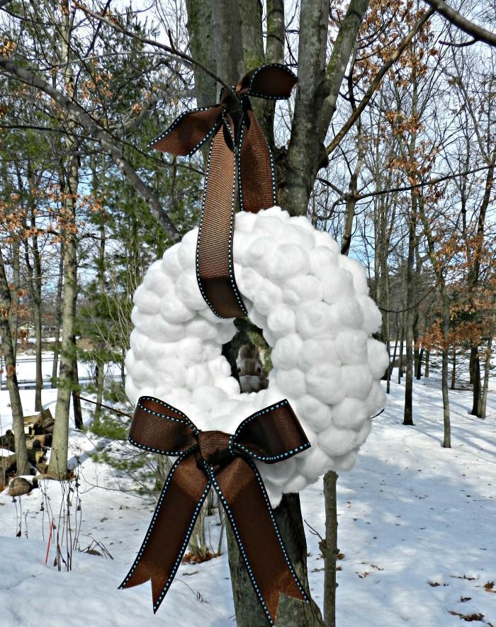 A large snowball wreath with a brown bow and a ribbon on top is a chic idea for winter