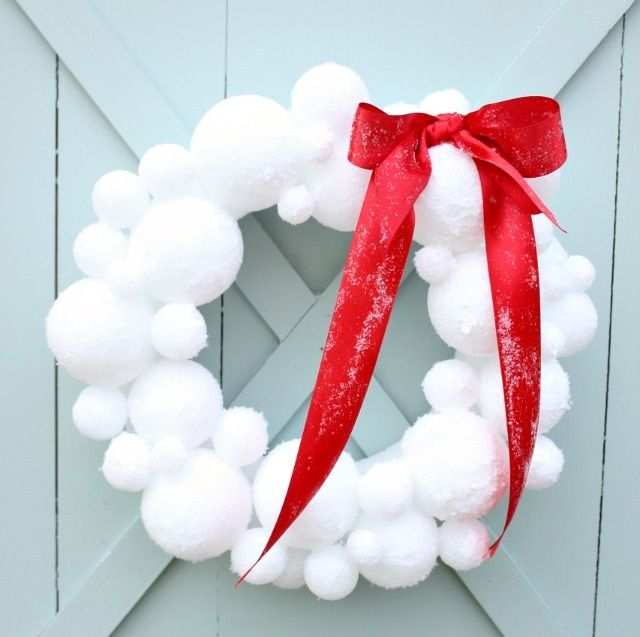 A snowball Christmas wreath accented with a large red bow will bring a snowy and fairy tale feel to the space