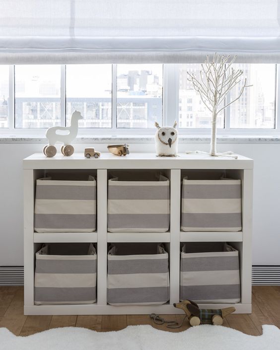 an open storage unit with fabric boxes that work as drawers give the nursery a neat look