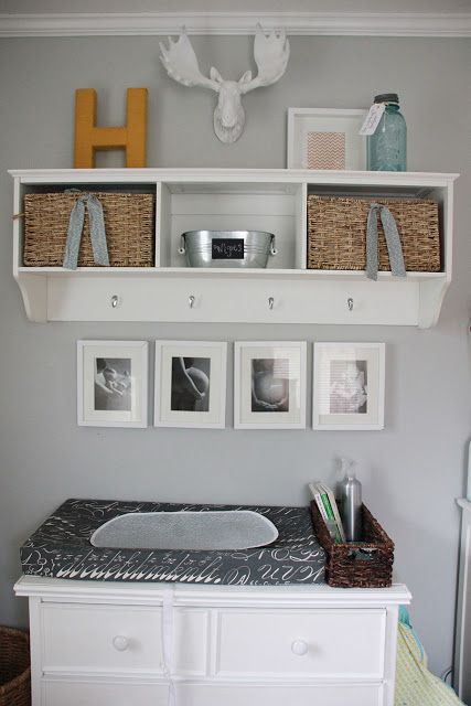 an open storage shelf with baskets and some hooks to store some stuff over the changing table