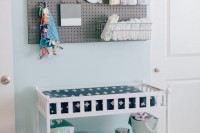a pegboard with wire baskets and a changing table with open storage spaces