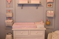 a changing table  with some shelves over it, shutters with baskets hanging on them