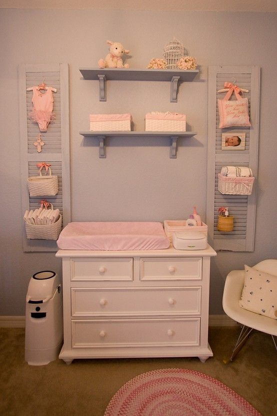 a changing table  with some shelves over it, shutters with baskets hanging on them
