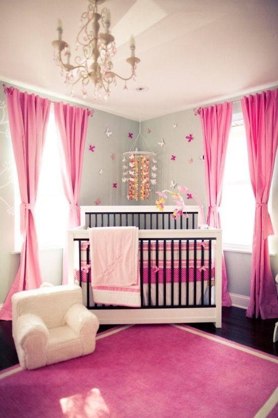 a bright girl's nursery with grey walls, hot pink textiles, a refined chandelier with pink crystals, a butterfly mobile