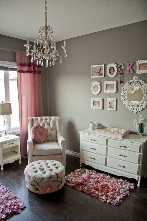a grey and pink vintage nursery with grey walls, white and creamy furniture, pink textiles, a gallery wall and a crystal chandelier