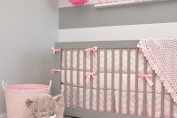 a modern and simple girlish nurseyr in grey and pink, with pink textiles, pink paper flowers and a small ledge gallery wall
