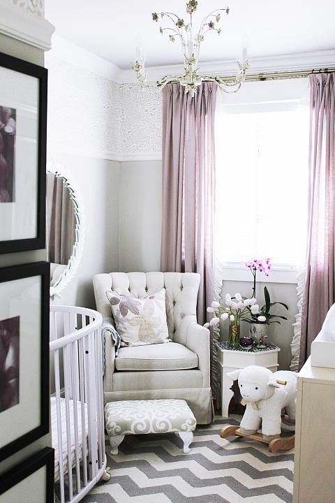 a small yet chic nursery with a chevron floor, color block walls, white and creamy furniture, mauve curtains and a floral chandelier