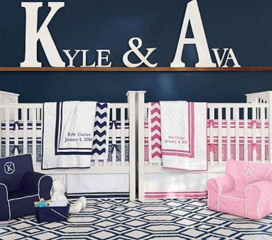 a blue and white shared nursery with navy, pink and white bedding and the names of the kids on the ledge