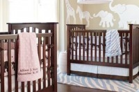 a neutral nursery in tan and white, with stained wooden cribs, with blue and pink printed linens is stylish and cute