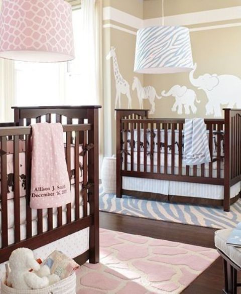 a neutral nursery in tan and white, with stained wooden cribs, with blue and pink printed linens is stylish and cute