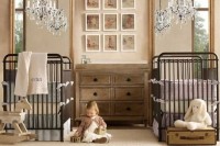 a neutral rustic nursery with dark forged beds, a wooden dresser, a gallery wall, crystal chandeliers and neutral toys