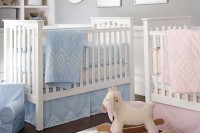 a grey and white shared nursery with white furniture, white monograms and artworks and pink and blue bedding