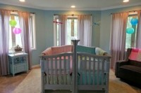 a colorful shared nursery with bright linens and lamps, with grey and blue furniture for fun