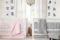 a neutral shared nursery with white walls and furniture, a beaded chandelier, photos and grey and pink bedding