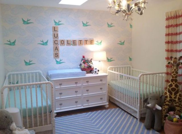 a neutral and pastel shared nursery with a skylight, a birdie wall, white furniture and pastel bedding and lots of toys