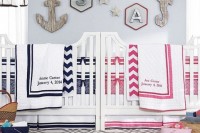 a nautical shared nursery with light blue walls, white furniture, a seaside gallery wall and navy and pink and white bedding
