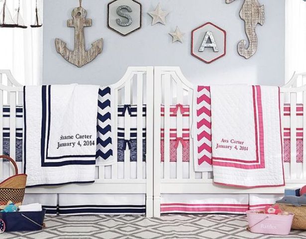 a nautical shared nursery with light blue walls, white furniture, a seaside gallery wall and navy and pink and white bedding