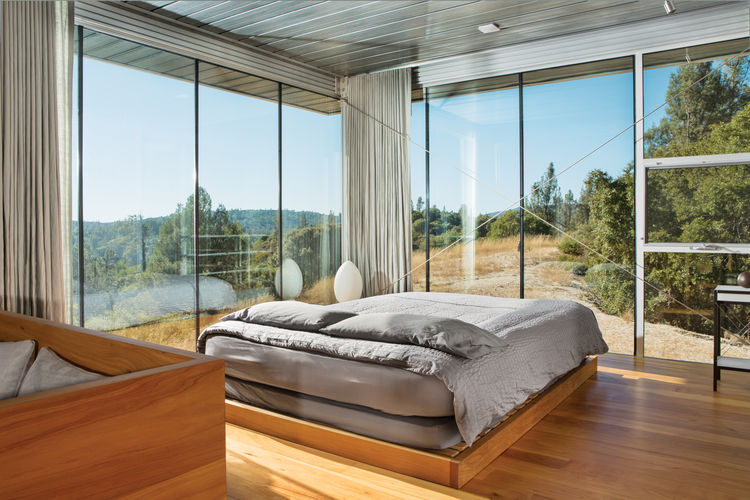 A stylish mid century modern bedroom with glazed walls is centered around the views that inspire and look fantastic and curtains allow to make it private
